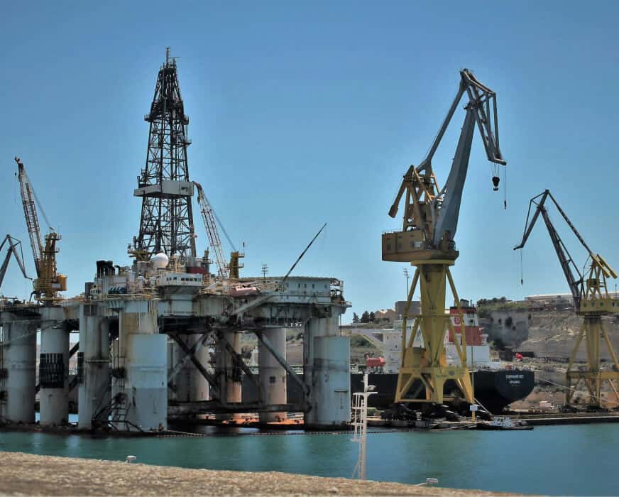 Oil platform with cranes at a port, related to manufacturing and industrial work.